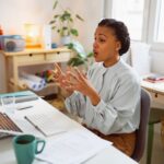 Woman in front of laptop gesticulating with hands